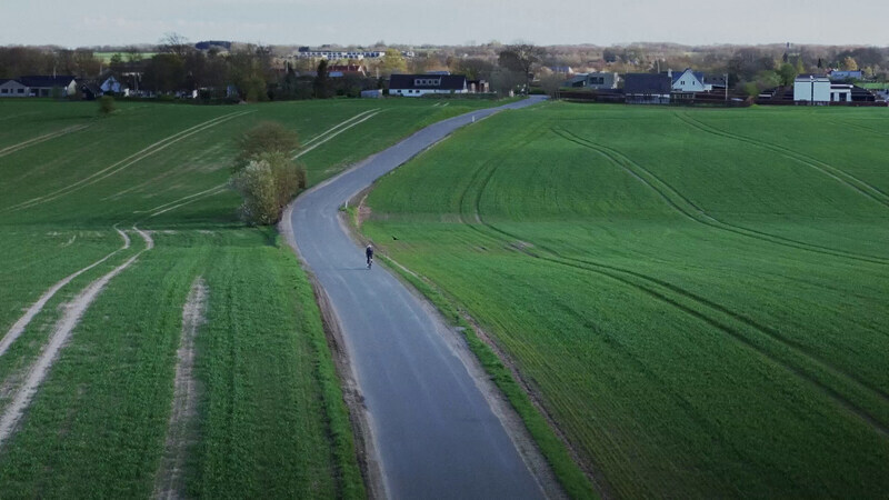 cyclist riding next to fields